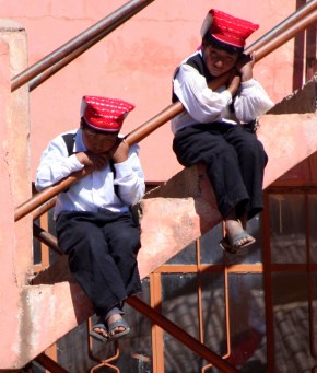 Two boys watch from a staircase vantage point