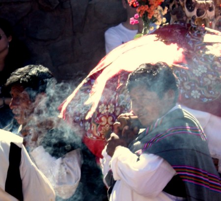 Altar boys carry the wreathed image of paired bulls.