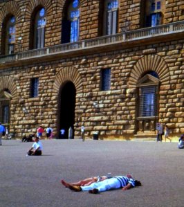 Tourists sun themselves in front of the Pitti Palace, Florence, Italy