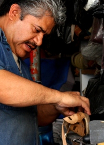 A cobbler works leather into footwear.